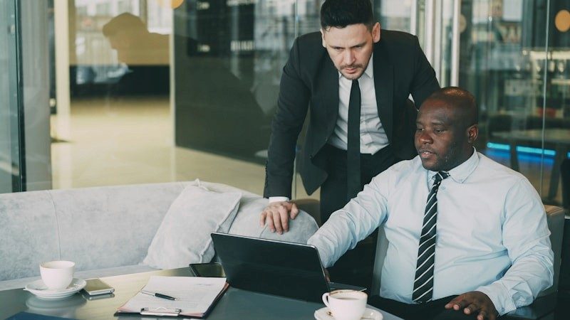 Dos personas revisando documentación en un portátil en una oficina