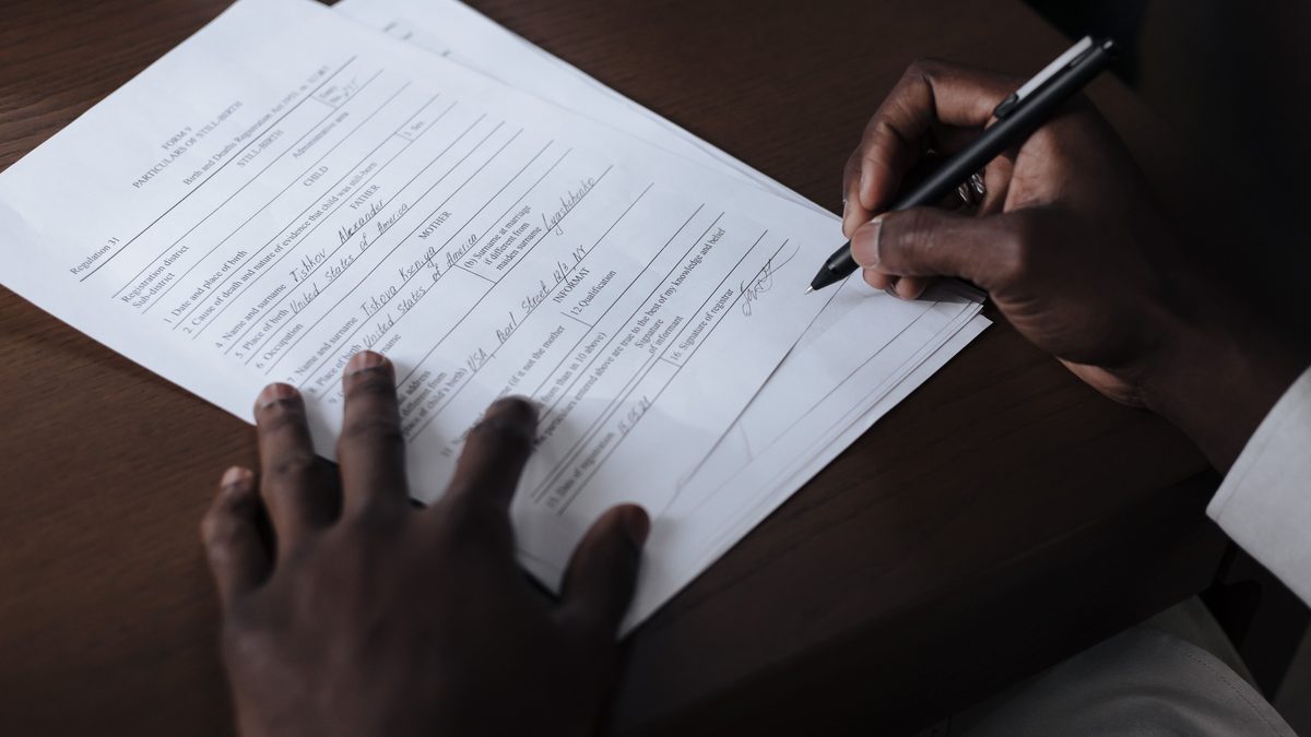 Manos firmando un documento laboral con un bolígrafo sobre una mesa