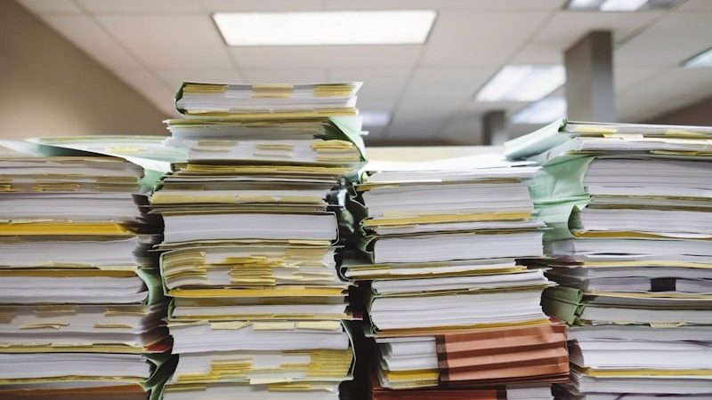 Montones de carpetas y expedientes apilados en una oficina